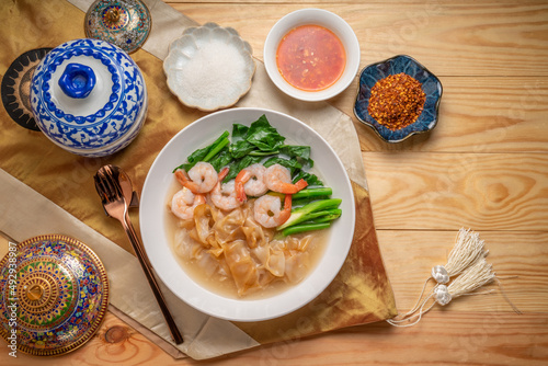 Wide Rice Noodles with Shrimp and kale in Gravy Sauce Served with condiments, chili powder , chili sauce and sugar. Asian food.