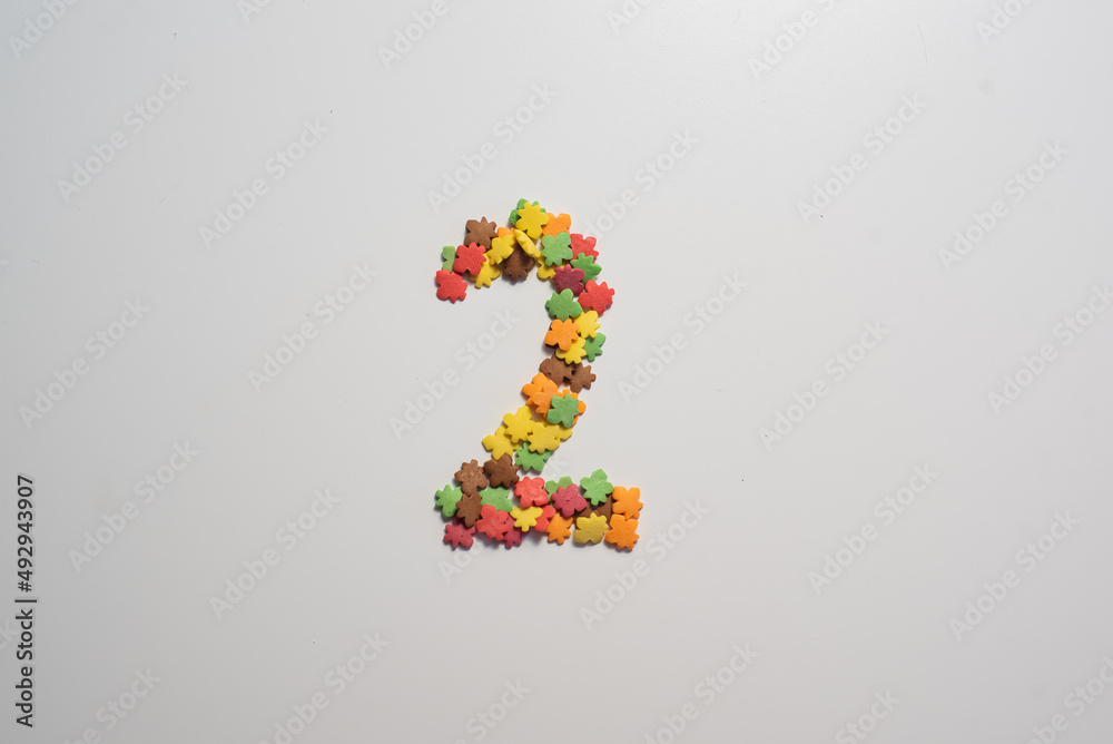 Numeral two from sweet pastry topping in the form of colorful foliage on a white background. Numeral two from sweet pastry topping in the form of colorful foliage on a white background.