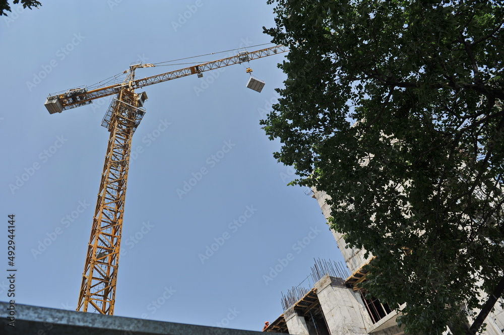 Almaty / Kazakhstan - 07.10.2012 : A tower crane lifts a stone slab over a construction site Almaty / Kazakhstan - 07.10.2012 : A tower crane lifts a stone slab over a construction site