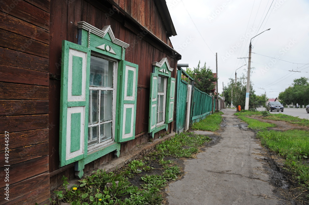 Petropavlovsk, Kazakhstan - 08.08.2013 : Wooden house along the street with decorative shutters at the window. Petropavlovsk, Kazakhstan - 08.08.2013 : Wooden house along the street with decorative shutters at the window.