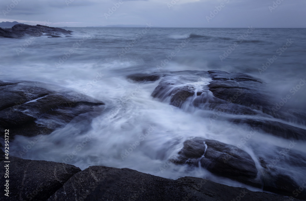 Beautiful long exposure shot of seascape at sunrise,silky smooth sea wave sweeping past the rock.