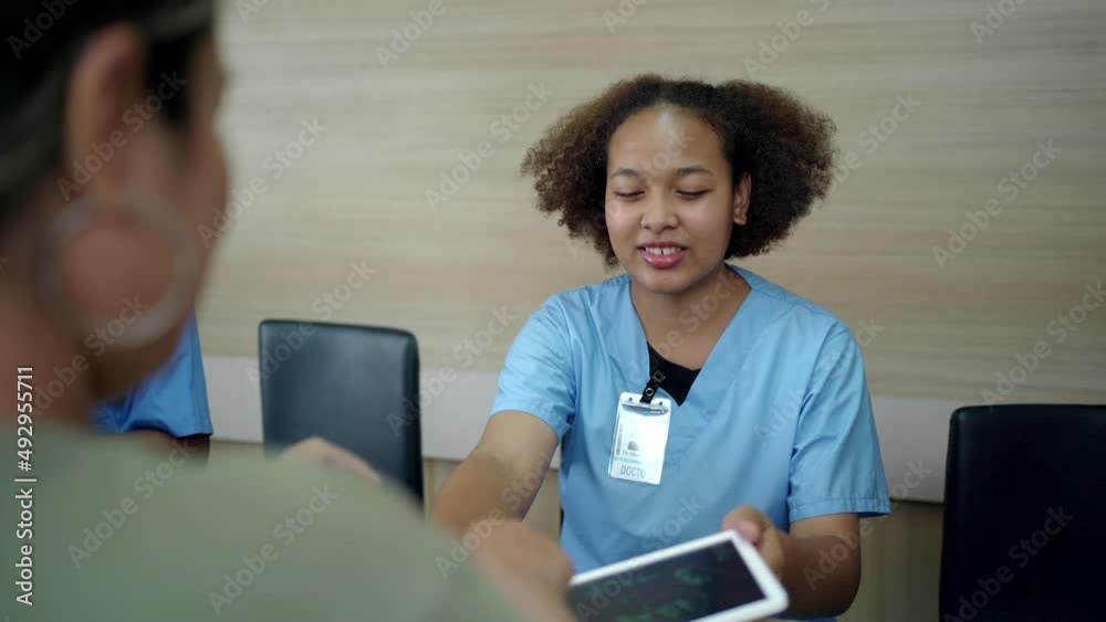 Patient talking to doctor at hospital desk and signing a document.