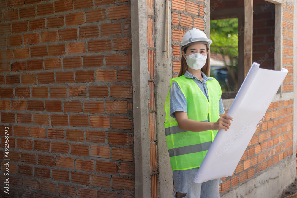 engineer concept The female engineer wearing a white mask and helmet holding her proposal paper of the construction