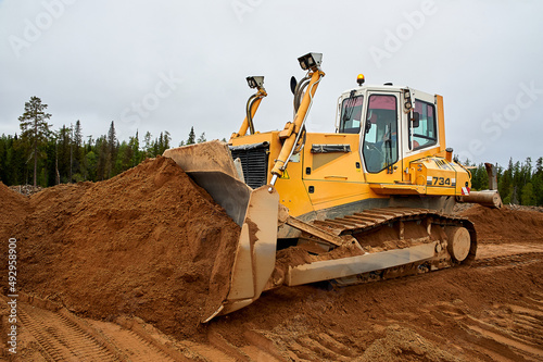 A yellow tractor levels the site with sand