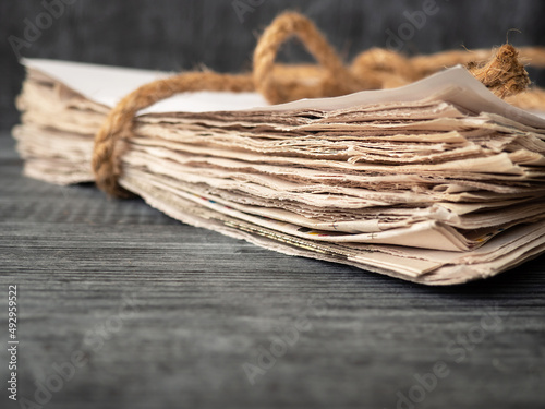 Stack of newspapers tied with a rope on a wooden background
