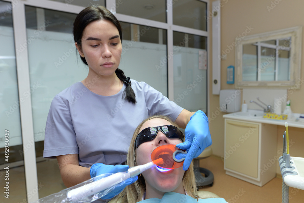 Dentist putting photopolymer filling using modern equipment