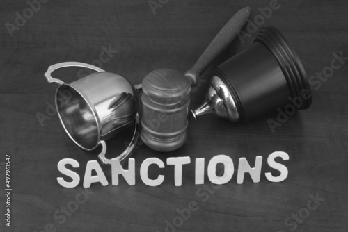 Broken trophy cup and gavel with letter sanctions. Cancellation of sport competitions concept.