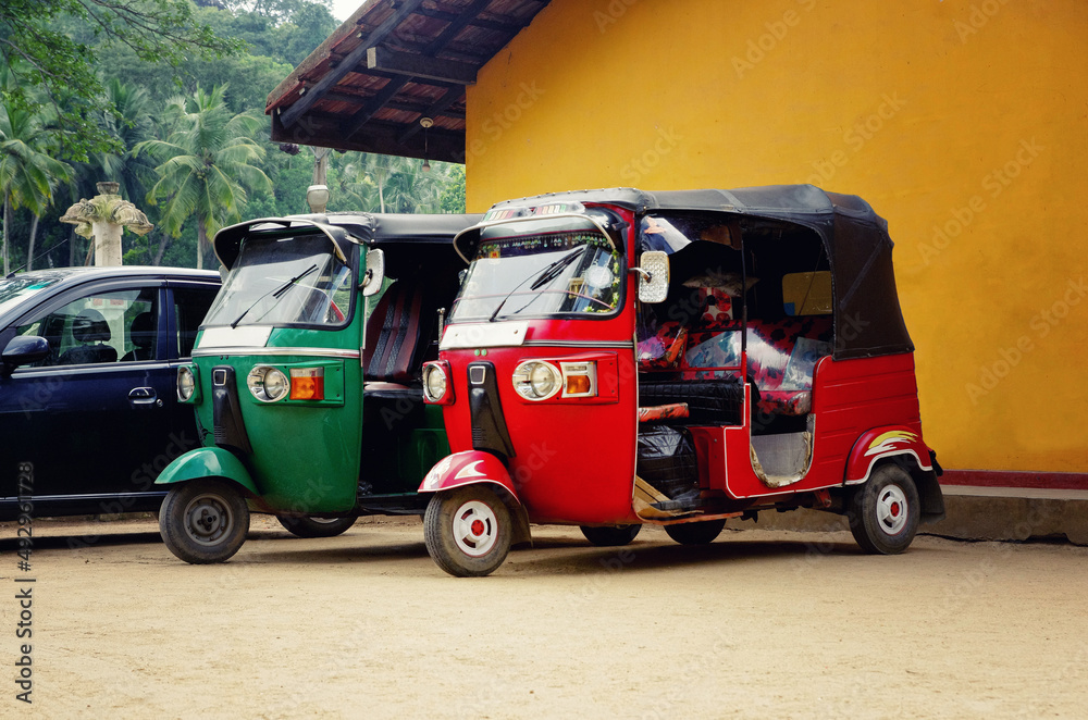 Tuk-tuk cars parked in the street of Sri Lanka. Famous tuk tuk taxi cars. Green and red tuk tuk.
