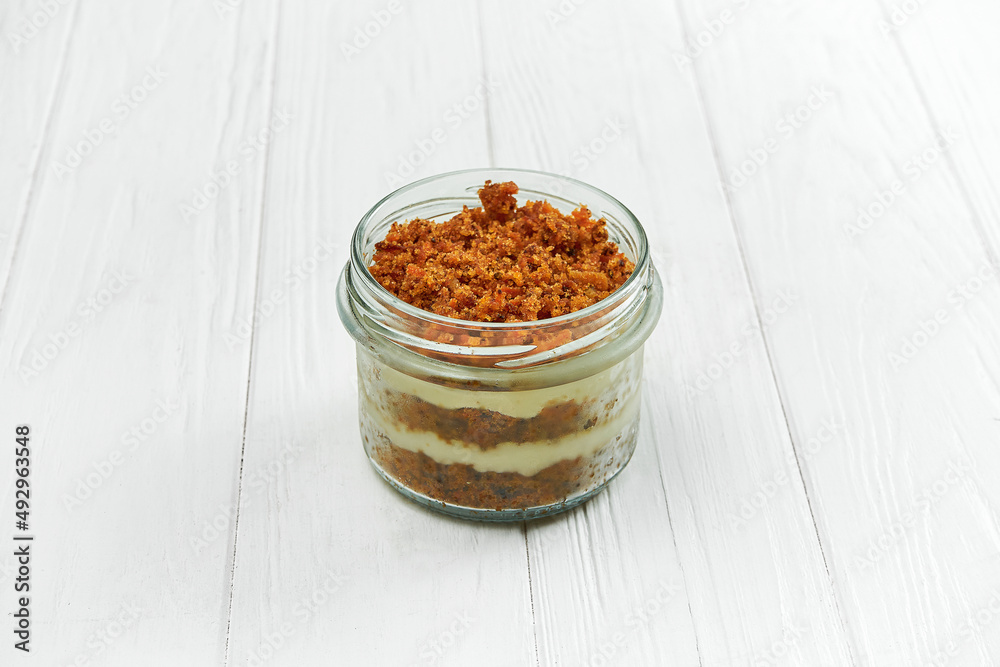 Sponge cake with cream in a jar on a white wooden background Sponge cake with cream in a jar on a white wooden background