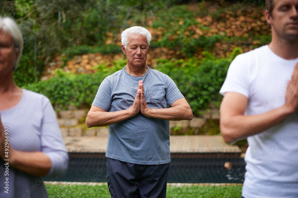 Deeply connected to his spirituality. Shot of a senior man meditating in an outdoor yoga class. Deeply connected to his spirituality. Shot of a senior man meditating in an outdoor yoga class.