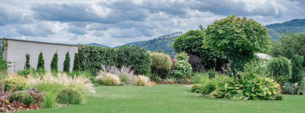 Ściana ozdobna w ogrodzie. Nowoczesna forma ogrodu. Piękny zadbany trawnik z rabatami - obrazy, fototapety, plakaty 