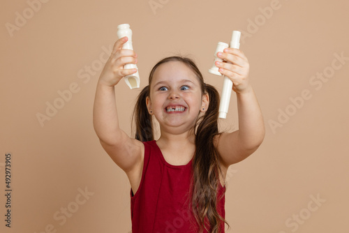 Girl in red dress hold flute disassembled in parts over head and gloat, beige background. Learning to play woodwind musical instrument. Flute and children is concept of music education development. photo