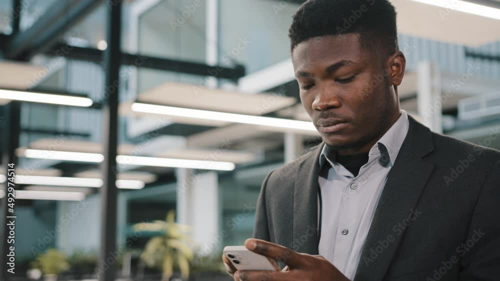 Thoughtful African man professional broker using mobile apps for online sales chatting with friend making order surfing internet focused analyst reading information typing message in social network Thoughtful African man professional broker using mobile apps for online sales chatting with friend making order surfing internet focused analyst reading information typing message in social network