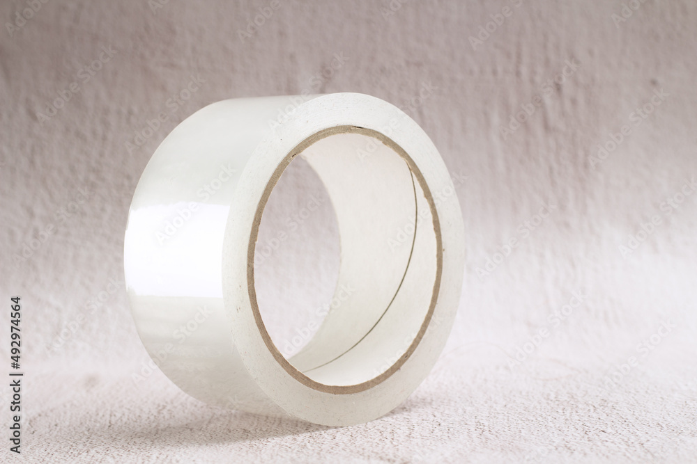 thick wide roll of transparent adhesive tape on a light rustic background thick wide roll of transparent adhesive tape on a light rustic background