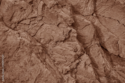 Light red brown rock texture. Cracked layered mountain surface. Close-up. Grungy stone background with space for design.