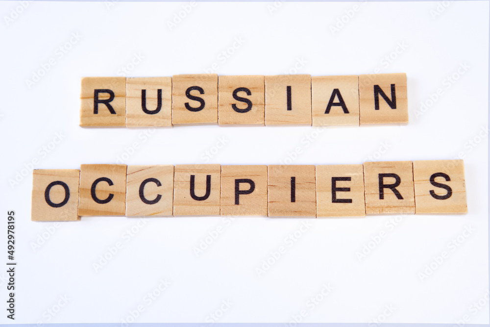 Top view of the words russian occupiers laid out from square wooden tiles isolated on white background.Concept of russian army, war in Ukraine, no war,support ukraine