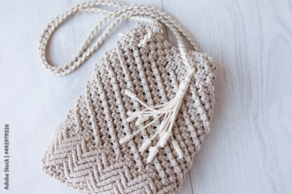 Obraz premium Handmade macrame bag. ECO friendly natural macrame cotton cross-body bag. Hobby knitting handmade macrame. Modern summer concept. Close up.