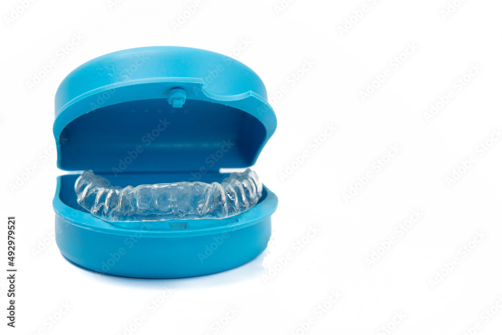 Blue dental prosthesis protective cover with prosthesis inside on white background leaving copy space. Oral hygiene concept showing a dental container to protect dentures and similar objects. Blue dental prosthesis protective cover with prosthesis inside on white background leaving copy space. Oral hygiene concept showing a dental container to protect dentures and similar objects.