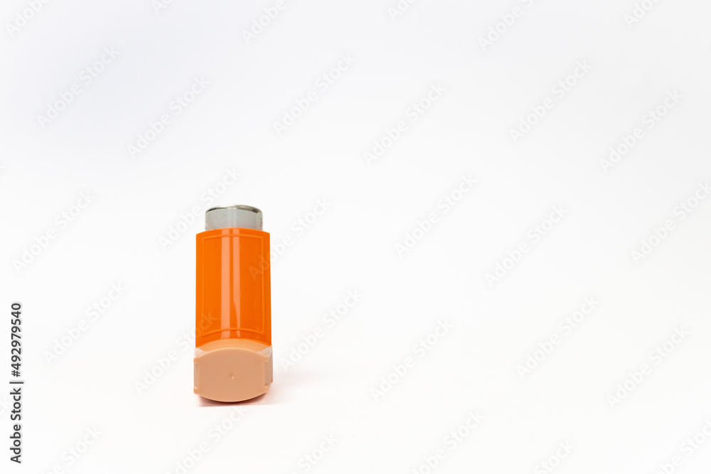 Front view of an orange aerosol spray canister inside leaving copy space. Basic and necessary tool for patients with asthma and similar diseases. Respiratory health concept. Front view of an orange aerosol spray canister inside leaving copy space. Basic and necessary tool for patients with asthma and similar diseases. Respiratory health concept.