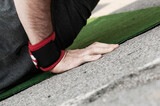 Close-up side view of a man's right hand with wrist band doing push ups on green mat