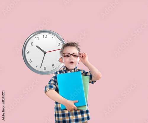 Smiling happy teen student boy hold books look at clock