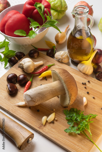 Autumn gifts of nature on a table with cutting board. Selection of mushroom, chestnuts, spices, paprika, garlic, onions, chayote, pomegranate and olive oil
