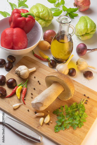 Selection of mushroom, chestnuts, spices, paprika, garlic, onions, chayote, pomegranate and olive oil on a table with cutting board