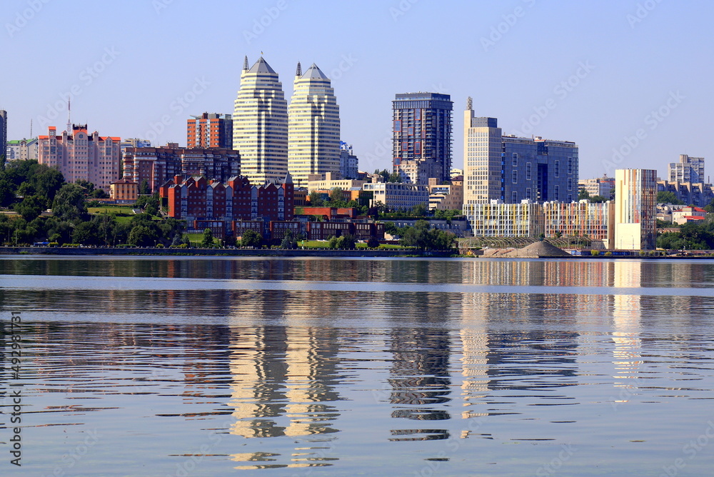 Big city on banks of wide river. Beautiful modern towers, buildings, skyscrapers are reflected in water in summer,Spring. Ukrainian city Dnipro, Dnepropetrovsk, Ukraine
