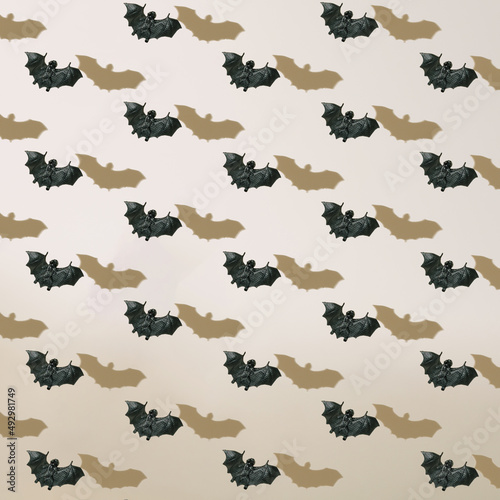 Halloween pattern of black flying bats with shadows on neutral beige background.