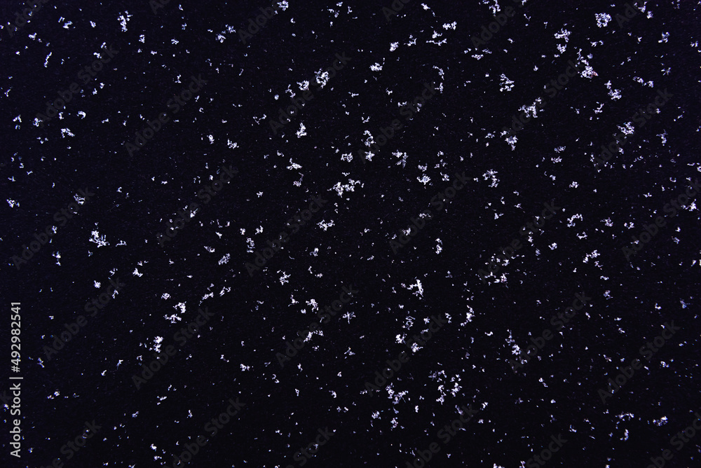 Black background texture with white snow crystals. Snow on a black background.