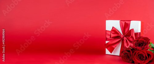  Box with red bow and red roses on red background for decoration. Promotional template. Holiday concept. Creative modern design.