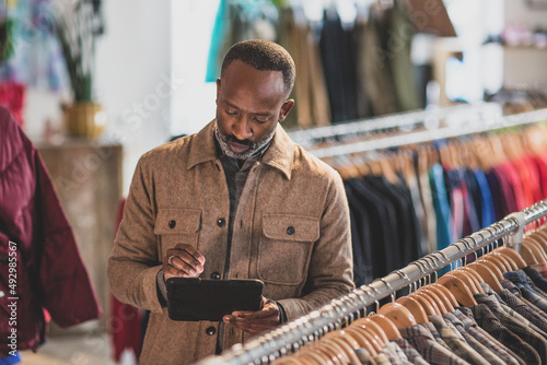 Store manager checking stock in a clothing store on a digital tablet