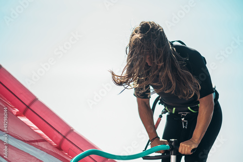 Woman preparing kiteboarding kite with the air pump photo