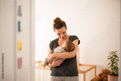 New Mum cradling her baby and smiling in her nursery