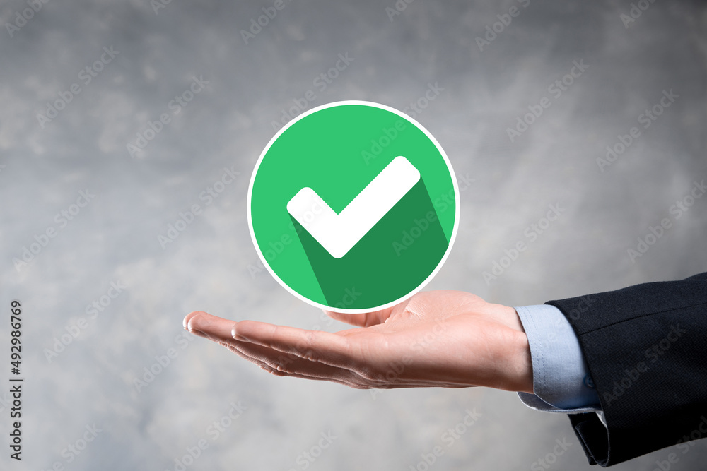 Hand holds green icon Check mark,Check Mark Sign, Tick Icon,right sign,circle green checkmark button,Done.On dark background.Banner.Copy space.Place for text. Hand holds green icon Check mark,Check Mark Sign, Tick Icon,right sign,circle green checkmark button,Done.On dark background.Banner.Copy space.Place for text.