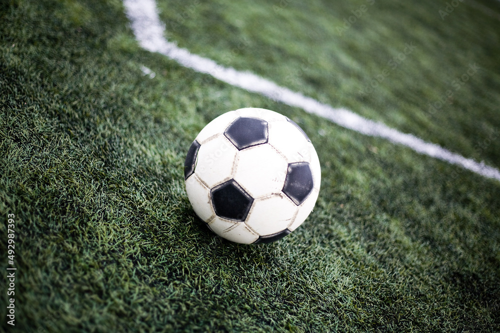 Obraz premium Soccer ball on grass. Football field background. Green lawn for playing football. Outdoor sport for health. Kick the ball soccer match.