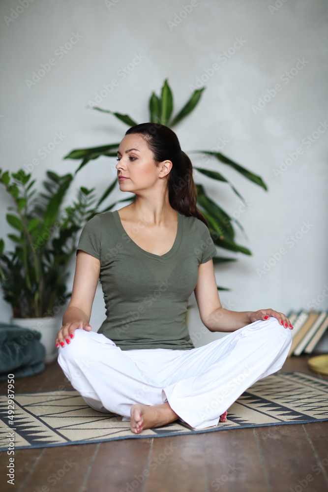 Young happy healthy fitness beautiful woman female doing and workout on yoga mat opposite at modern bedroom at home.