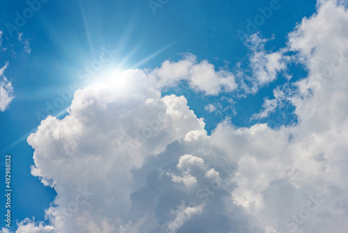 Beautiful blue sky with white cumulus clouds and sun rays  sunbeams . Backlight photography.
