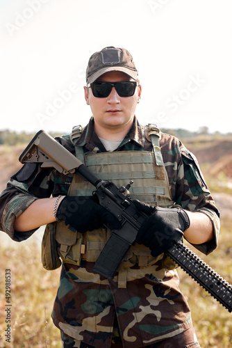 Soldier portrait. Military action in field. Ground gun battle. Fully equipped military forces in operations. Airsoft recreation sports. Soldier in tactical equipment. Outdoor, look at camera
