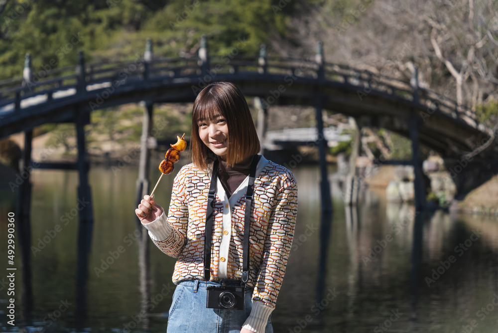 日本庭園で団子を食べる女性