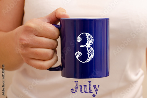 The inscription on the blue cup 3 july. Cup in female hand, business concept