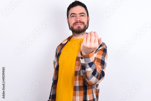young caucasian man wearing plaid shirt over white background, inviting you to come, confident and smiling making a gesture with hand, being positive and friendly.