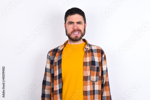 young caucasian man wearing plaid shirt over white background being nervous and scared biting lips looking camera with impatient expression, pensive.