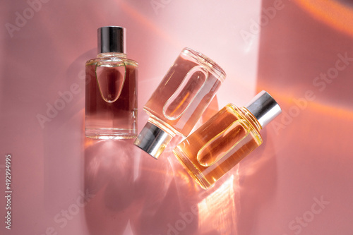 Obraz na plátně Transparent bottles of perfume on a pink background
