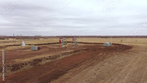 Pump jack in vast oil fields in Russia. Pipelines transporting oil from oil pumps, aerial drone shot
