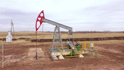 Pump jack in vast oil fields in Russia. Pipelines transporting oil from oil pumps, aerial drone shot
