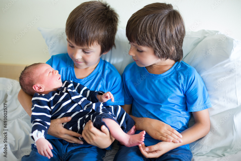 Two boys, brothers, meeting for the first time their new baby brother at hospital Two boys, brothers, meeting for the first time their new baby brother at hospital