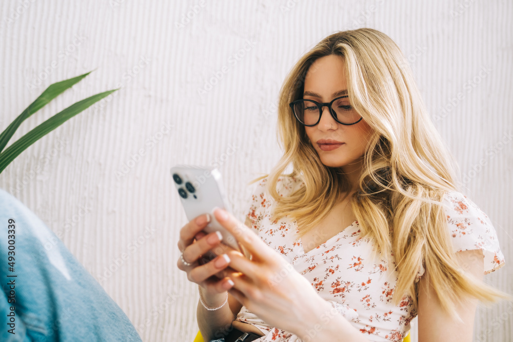 Young attractive woman sitting on a chair and using mobile phone. Young attractive woman sitting on a chair and using mobile phone.
