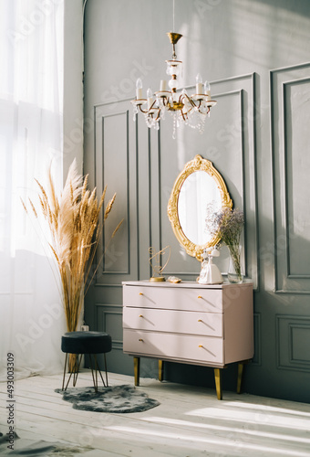 Interior of contemporary living room with dresser and vintage mirror on a wall.