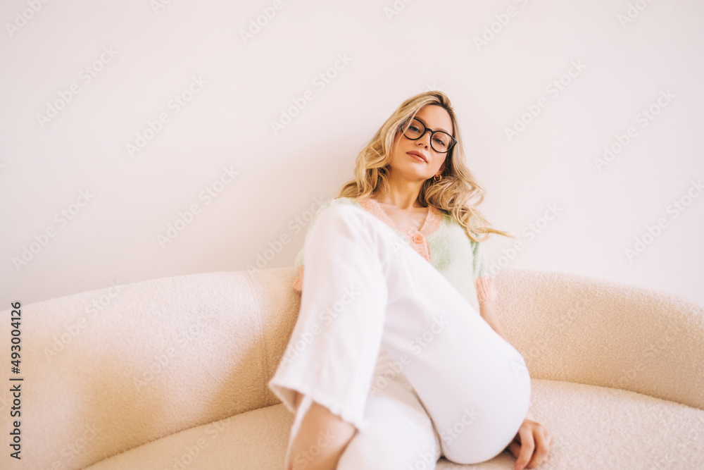 Portrait of young attractive stylish caucasian woman in eyeglasses sitting on a sofa. Portrait of young attractive stylish caucasian woman in eyeglasses sitting on a sofa.